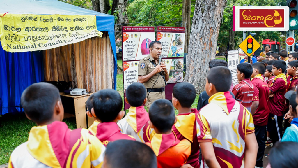 Headline: මාතලේ විජය ජාතික පාසලේදී 'ටේක්කෙයාර්' මාර්ග ආරක්ෂණ වැඩසටහන අද Intended image subject: Matale Vijaya National School entrance or students learning road safety Story summar