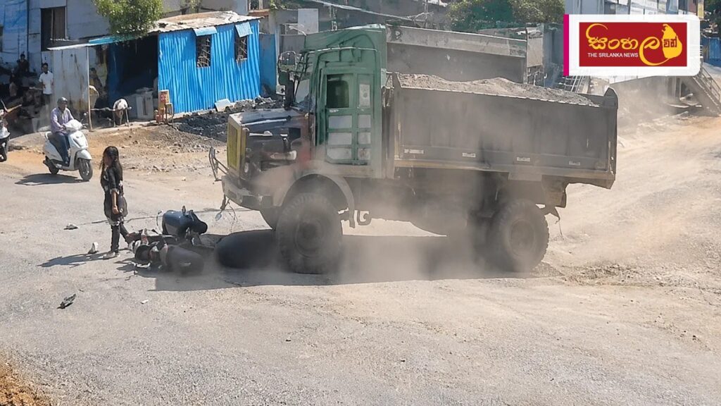 ඉන්දියාවේදී ටිපර් රථයක ගැටුණු තරුණියක් දිවි බේරා ගනී Headline: ඉන්දියාවේදී ටිපර් රථයක ගැටුණු තරුණියක් දිවි බේරා ගනී Intended image subject: CCTV footage of a woman hanging onto a truck bumper after an accident Story summary: ඉන්දියාව